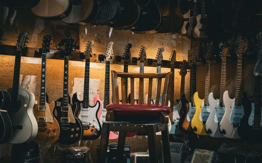 An acoustic and an electric guitar standing together in a warmly lit room